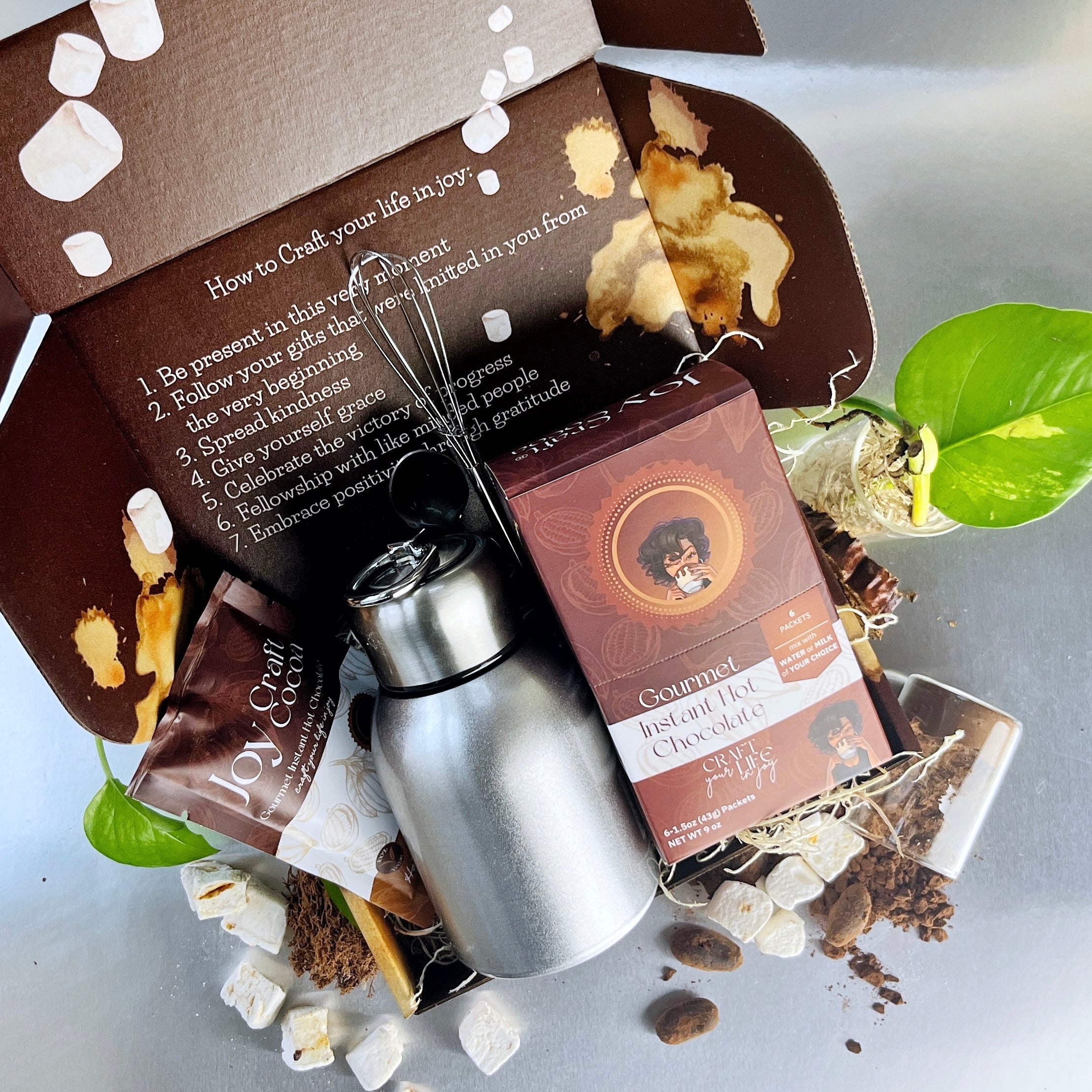 a photo of a hot chocolate gift box with cocoa, whisk, spoon, thermos
